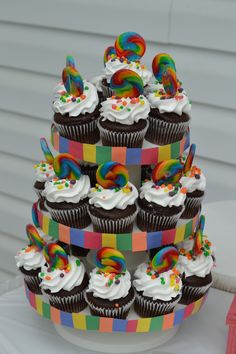 cupcakes with white frosting and rainbow toppings on a multi - colored cake stand