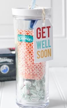 a glass jar filled with yarn and a tag that says get well soon on it