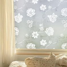 a window with white flowers on it next to a bed