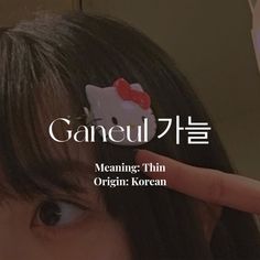 a woman holding up a hello kitty brooch in front of her face with the words gangeul on it