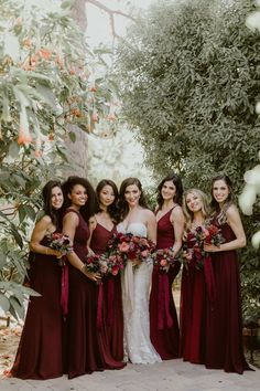 a group of women standing next to each other holding bouquets in their hands and posing for the camera