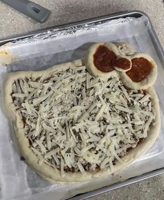 an uncooked pizza sitting on top of a pan covered in cheese and sauce