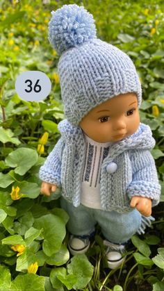 a doll is standing in the grass wearing a blue jacket and hat with a number on it