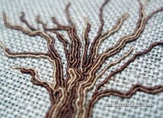 a close up view of a tree embroidered on a piece of cloth with brown thread