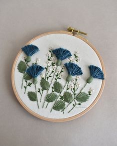 a close up of a embroidery on a hoop with flowers and leaves in the middle