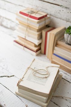 a stack of books sitting on top of a wooden table next to a potted plant