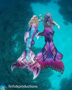 two mermaids are swimming in the ocean together