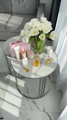 a table with flowers and personal care items on it in front of a couches window