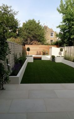 an outdoor garden with grass and trees in the back yard, surrounded by white walls