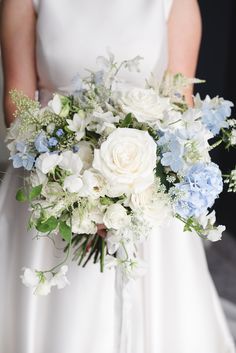 a bride holding a bouquet of white and blue flowers