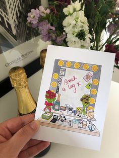 a hand holding up a card that says thank you on the counter with flowers in the background