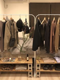 clothes are hanging on racks in a room with wooden floors and white walls, along with other clothing items