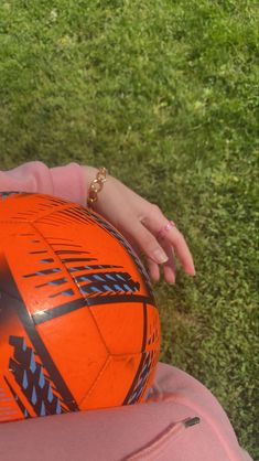 a close up of a person's hand holding an orange soccer ball