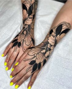 a woman's hands with yellow fingernails and tattoos on her arms, both holding flowers