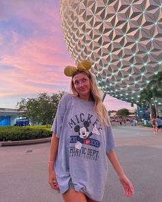 a woman standing in front of the spaceship dome at disney's animal kingdom with her hand on her hip