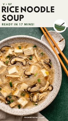 a bowl of rice noodle soup with chopsticks next to it on a green surface