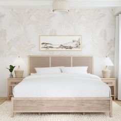 a bedroom with a bed, nightstands and pictures on the wall above it in neutral colors