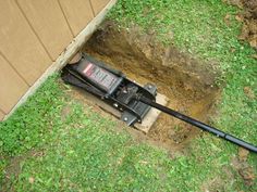 a hole dug in the ground with a lawn mower laying on it's side