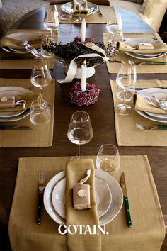 A Christmas table setting featuring mustard woven linen napkins, dried floral centerpieces with ribbon, and rustic decor on a wooden table.