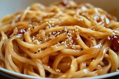 a bowl filled with noodles covered in sauce and sesame seeds