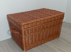 a brown wicker basket sitting on the floor next to a white wall and wooden floors