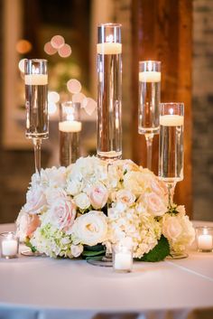 flowers and candles are arranged on the table for an elegant centerpiece at this wedding reception