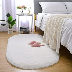 a bedroom with white bedding and a pink slipper laying on the floor in front of it