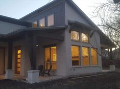 a house that has some lights on in the front and side of it with windows