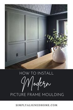 an empty dining room with black walls and wooden table in the foreground text reads how to install modern picture frame molding