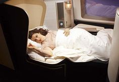 a woman laying in a bed on an airplane