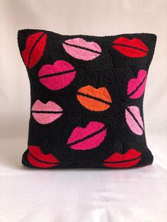 a black pillow with pink and red lips on it