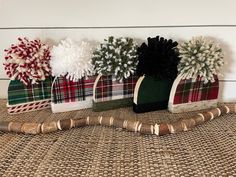 three christmas stockings with pom - poms are lined up on a tablecloth