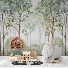 a toy elephant sitting in front of a forest mural