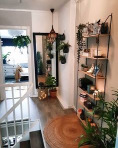 an entry way with plants and candles on shelving units next to the stairs leading up to the second floor