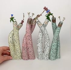 four small vases with flowers in them are being held by someone's hand