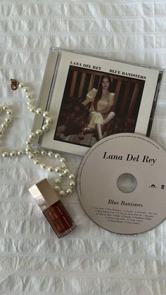 a cd and necklace laying on top of a white sheet