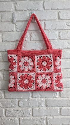 a pink crocheted bag hanging on a brick wall next to a white brick wall