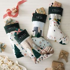 three christmas stockings with personalized socks on them next to some cookies and candies