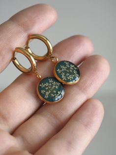 a person is holding two gold rings with flowers on them and one has a green background