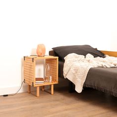 a bed sitting next to a night stand on top of a hard wood floor