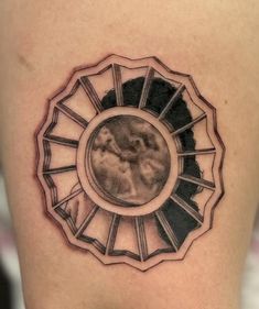 a woman's thigh with a tattoo on it that has an image in the center