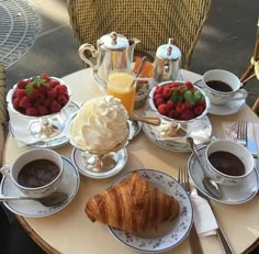 an assortment of breakfast foods on a table with coffee, fruit and croissants