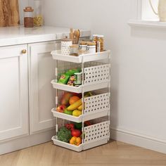 a kitchen with white cabinets and drawers filled with fruits, vegetables and other things on the shelves