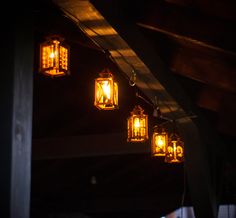 some yellow lights hanging from a roof in the dark