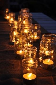 many lit candles are lined up on a table