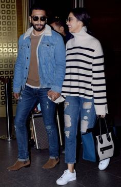 a man and woman holding hands while walking through an airport