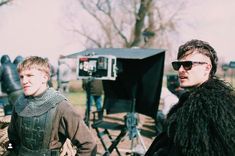 two men standing next to each other in front of a camera set up for filming