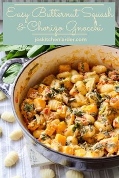 a pot filled with pasta and spinach on top of a table next to garlic