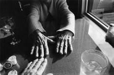 an old woman sitting at a window sill with her hands on the windowsill