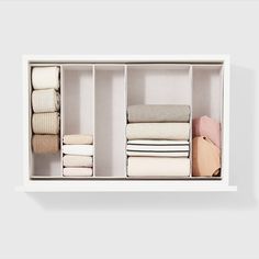 an organized closet with folded linens and folded towels on shelves in white painted wall